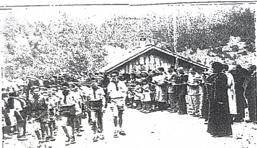 Page 44 de l'album, 1952 : rassemblement devant un petit bâtiment de bois.