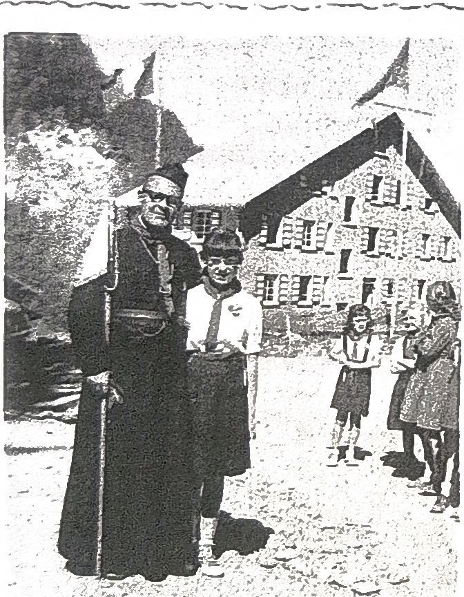Page 31 de l'album : un prêtre en soutane et des enfants devant le chalet. Les personnes ne sont pas nommées sur la page.