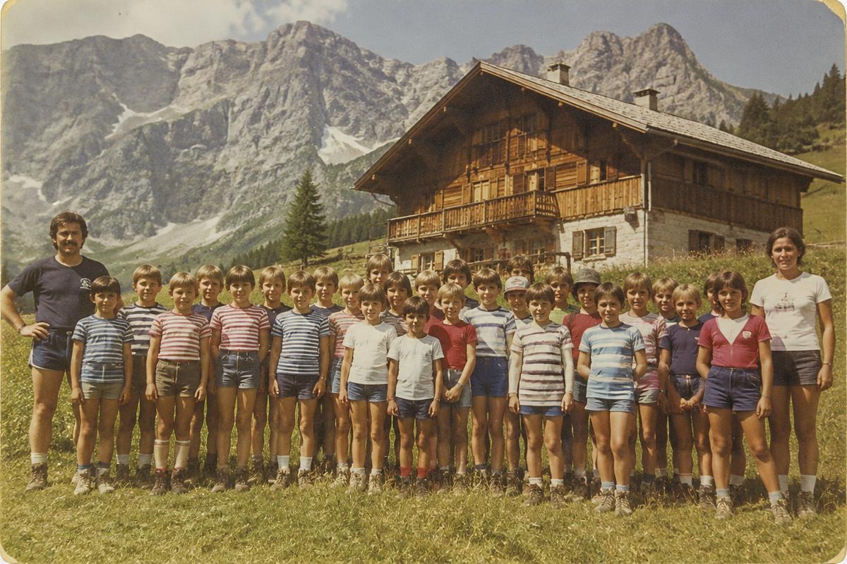 Photo vintage des enfants de la colonie alignés sur la prairie devant le grand chalet de Salavagny, falaises du cirque derrière